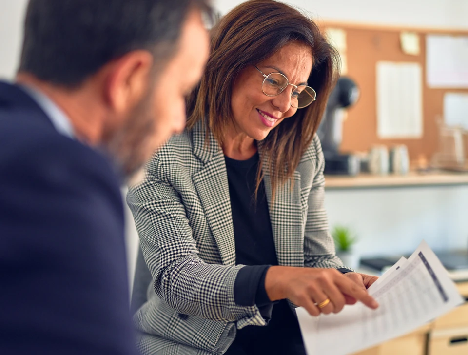 A woman showing a man a sheet of finances.